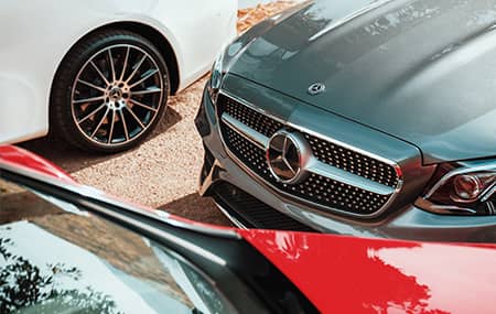 Red, white and gray Mercedes-Benz vehicles are parked near each other.